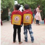 Two children stand together with Abhayudaan School Bag